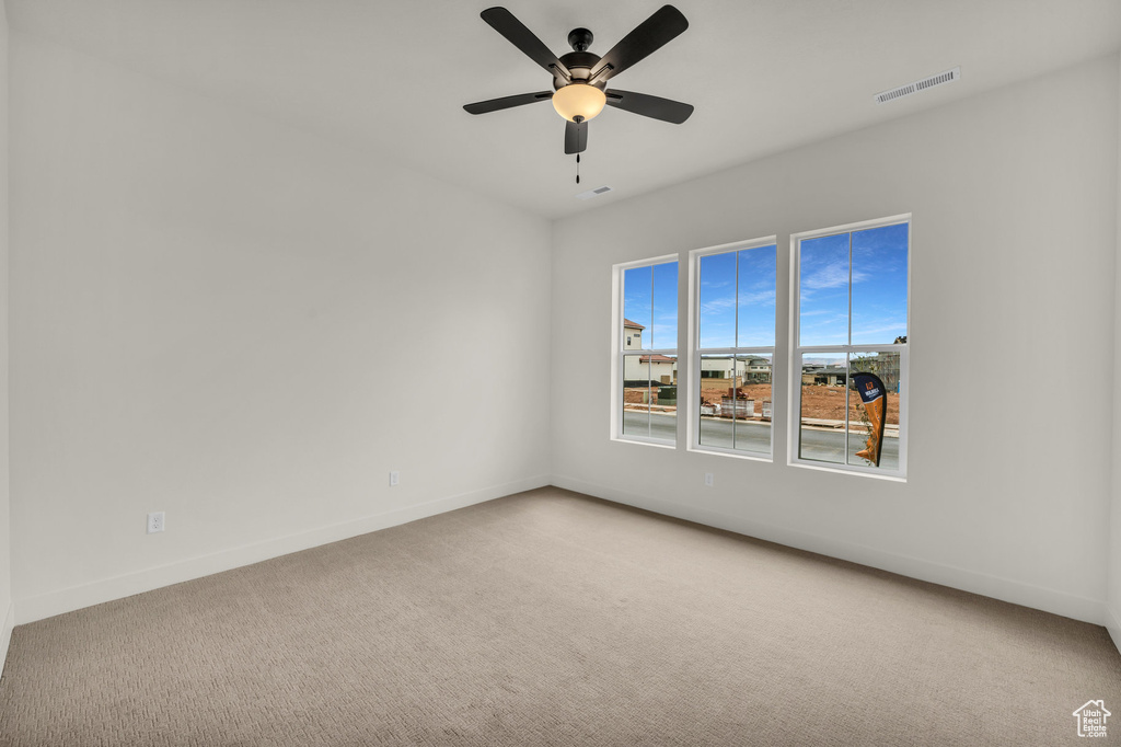 Carpeted spare room featuring ceiling fan