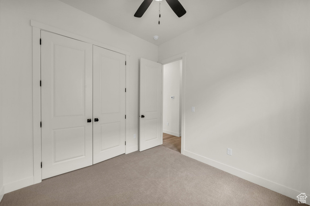 Unfurnished bedroom with light carpet, a closet, and ceiling fan