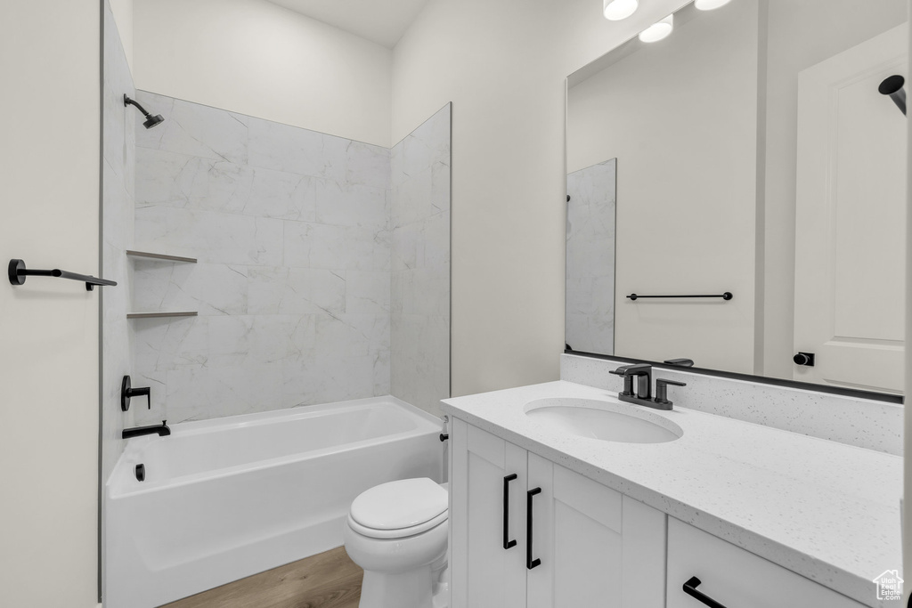 Full bathroom featuring tiled shower / bath combo, vanity, toilet, and wood-type flooring