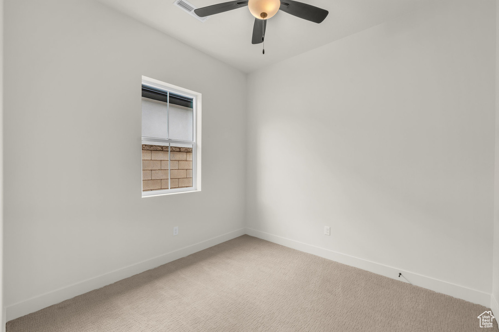 Carpeted empty room featuring ceiling fan