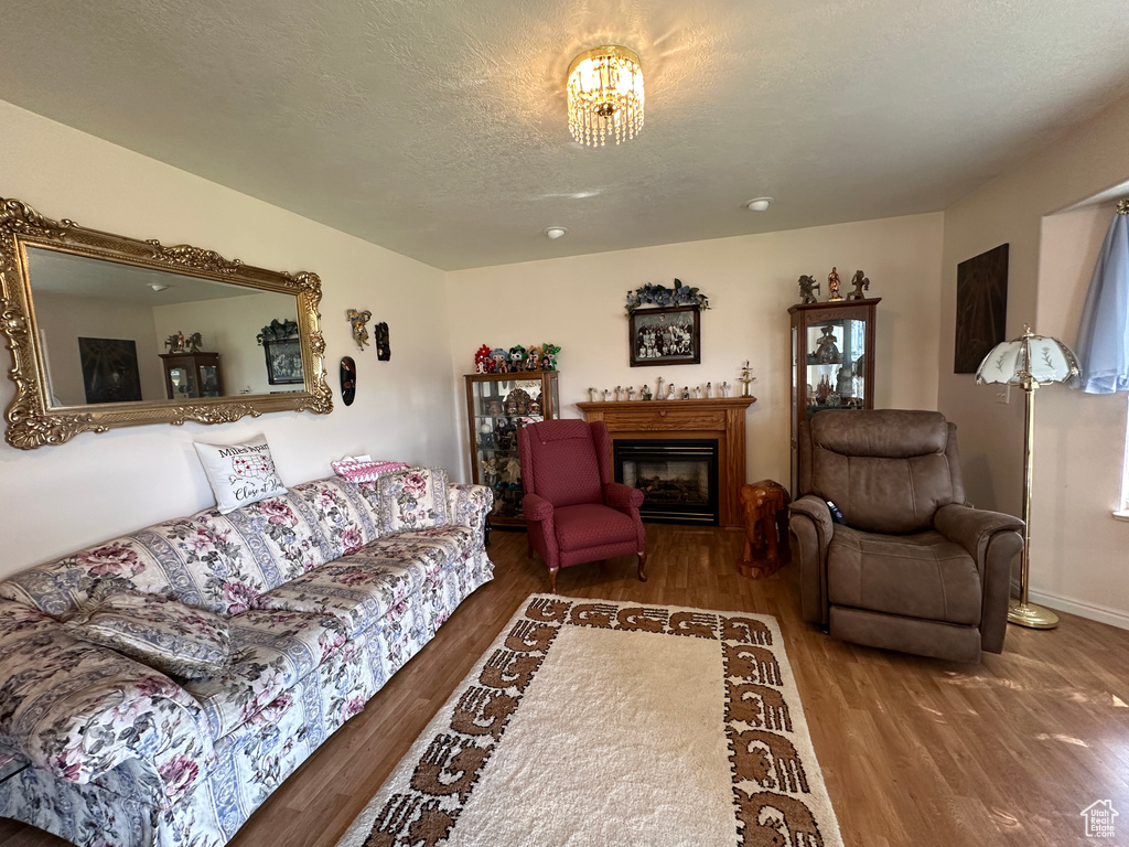 Living room with a chandelier, hardwood / wood-style flooring, and a textured ceiling