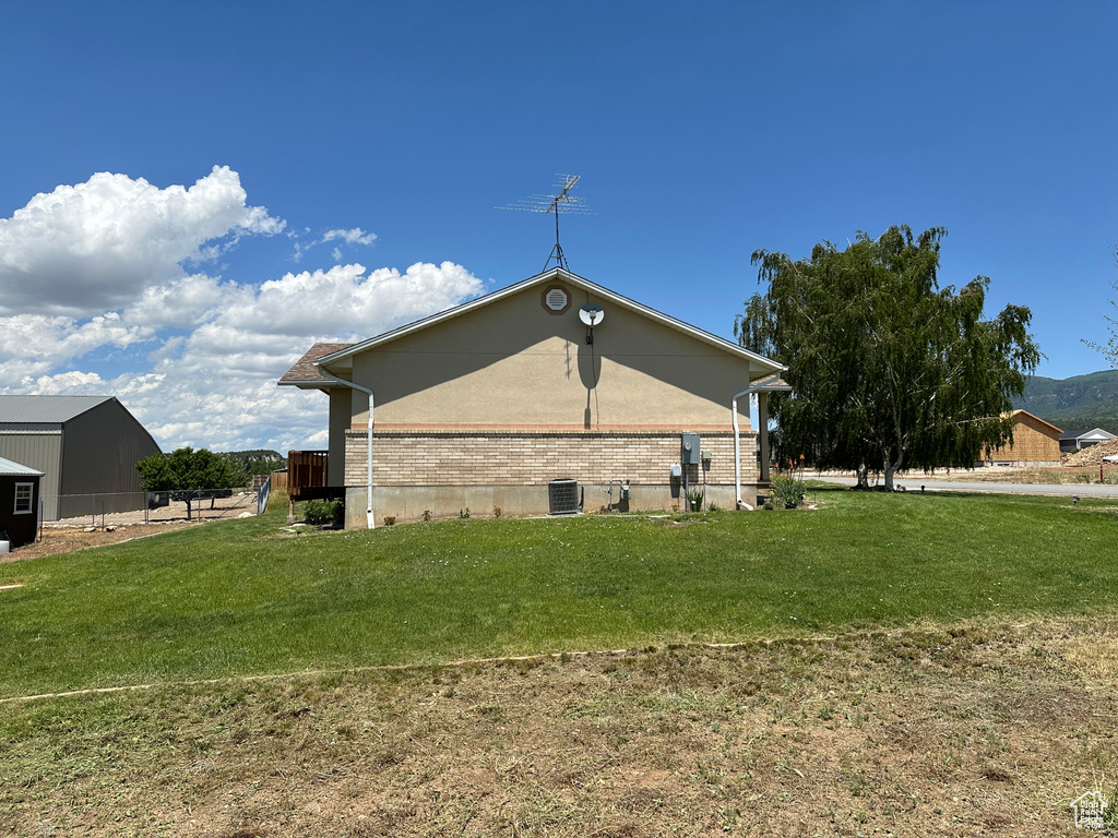 View of property exterior with central AC and a lawn