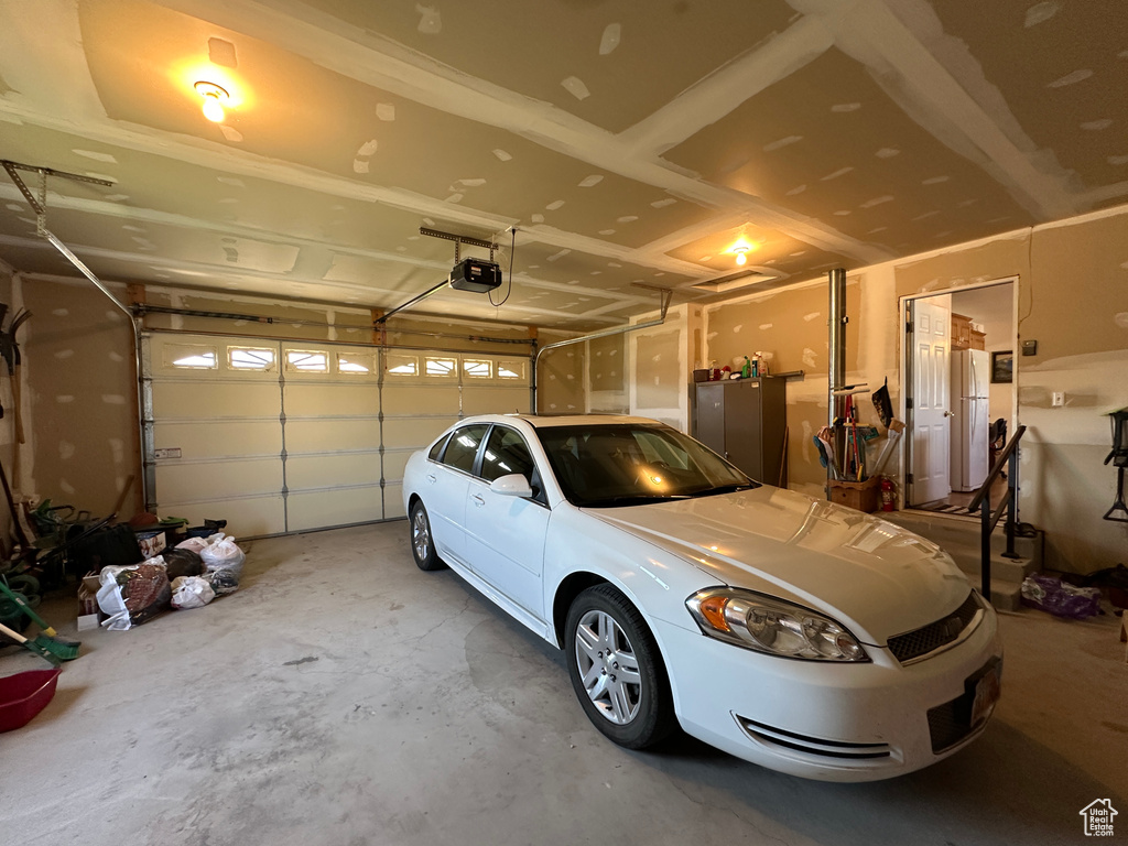 Garage with a garage door opener and white fridge