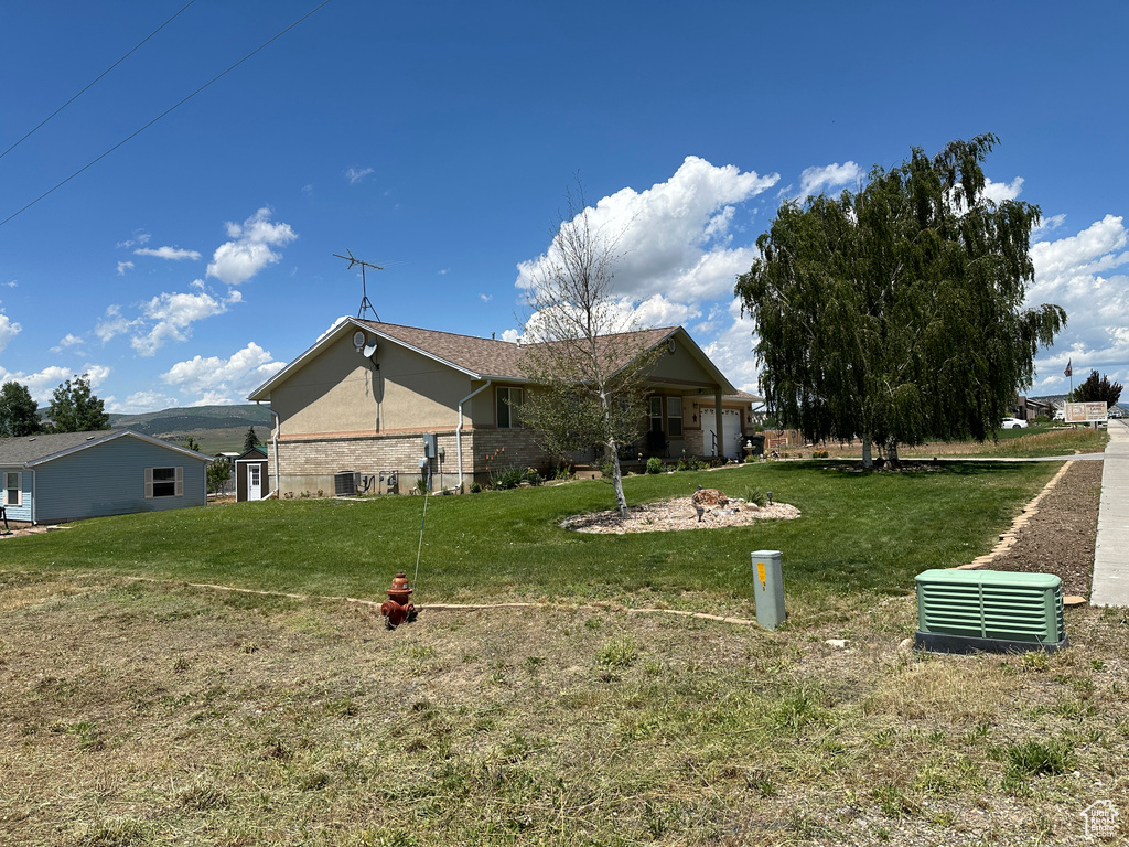 Rear view of house with a lawn and central AC unit