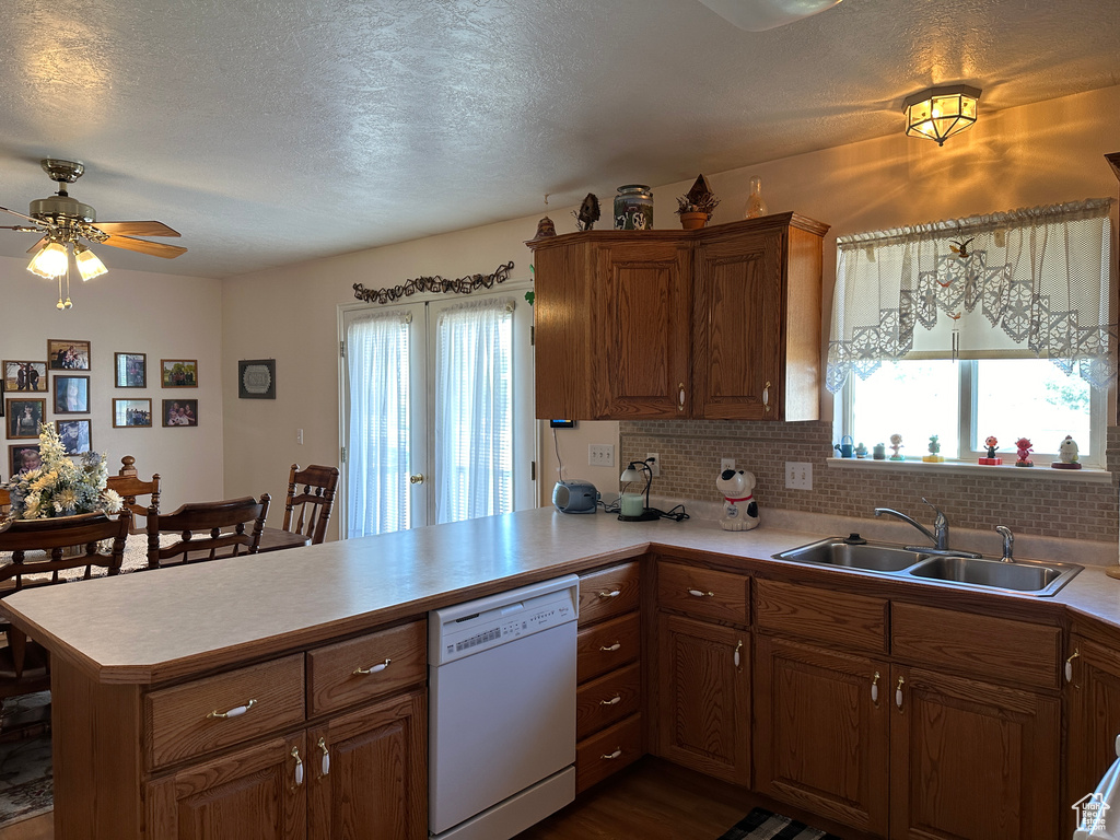 Kitchen with white dishwasher, sink, plenty of natural light, and kitchen peninsula