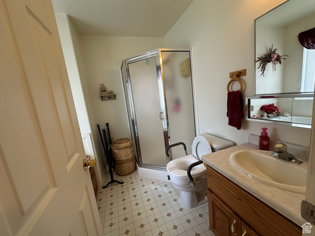 Bathroom featuring a shower with door, tile flooring, vanity with extensive cabinet space, and toilet