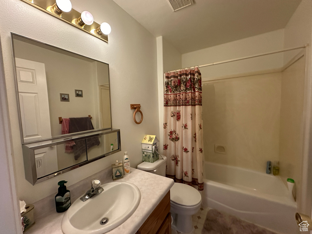 Full bathroom featuring shower / bath combination with curtain, large vanity, and toilet