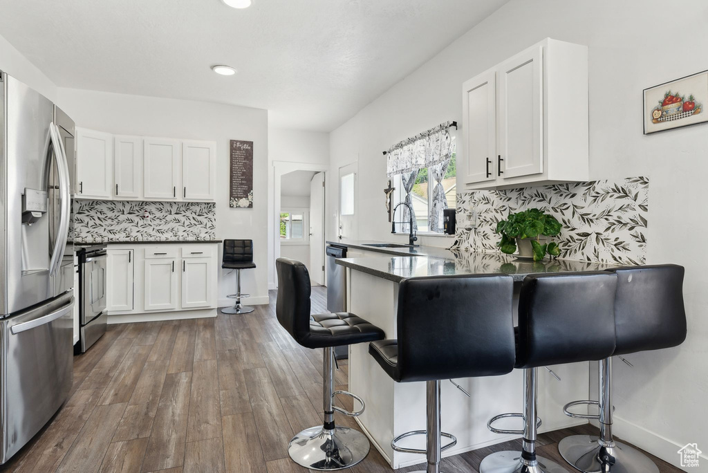 Kitchen featuring backsplash, white cabinetry, and appliances with stainless steel finishes