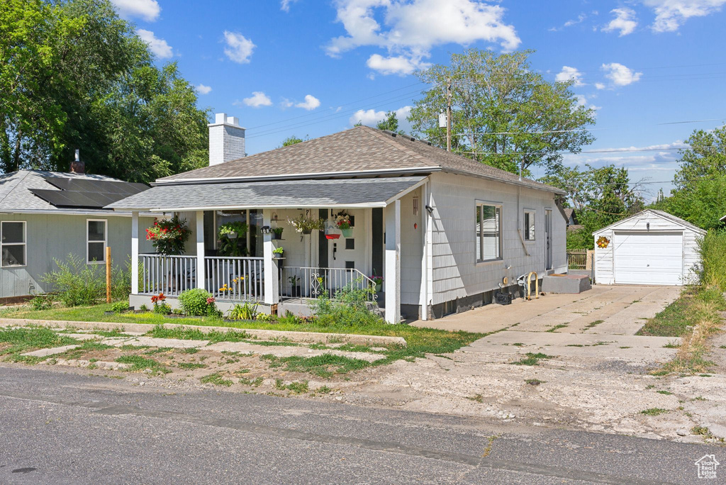 View of front facade with a garage, an outdoor structure, a porch, and solar panels