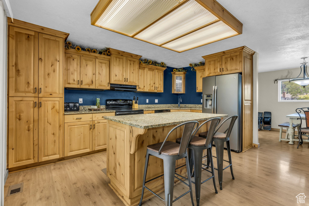 Kitchen featuring a center island, light wood-type flooring, electric range, stainless steel refrigerator with ice dispenser, and fume extractor