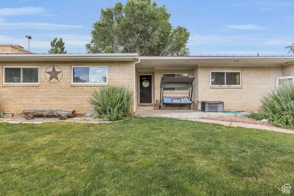 Rear view of property with central AC, a carport, and a lawn