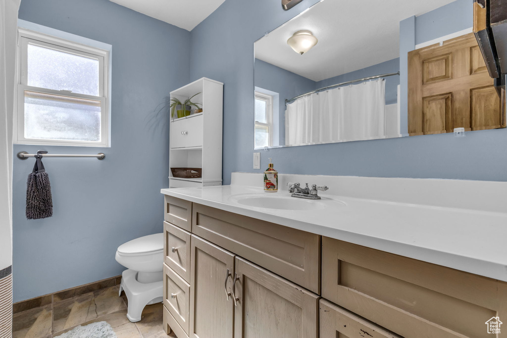 Bathroom with tile floors, a wealth of natural light, toilet, and vanity