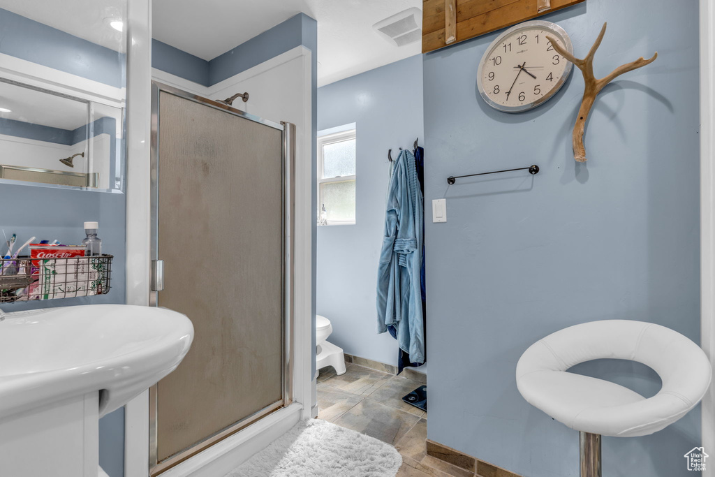 Bathroom with walk in shower, tile flooring, sink, and toilet