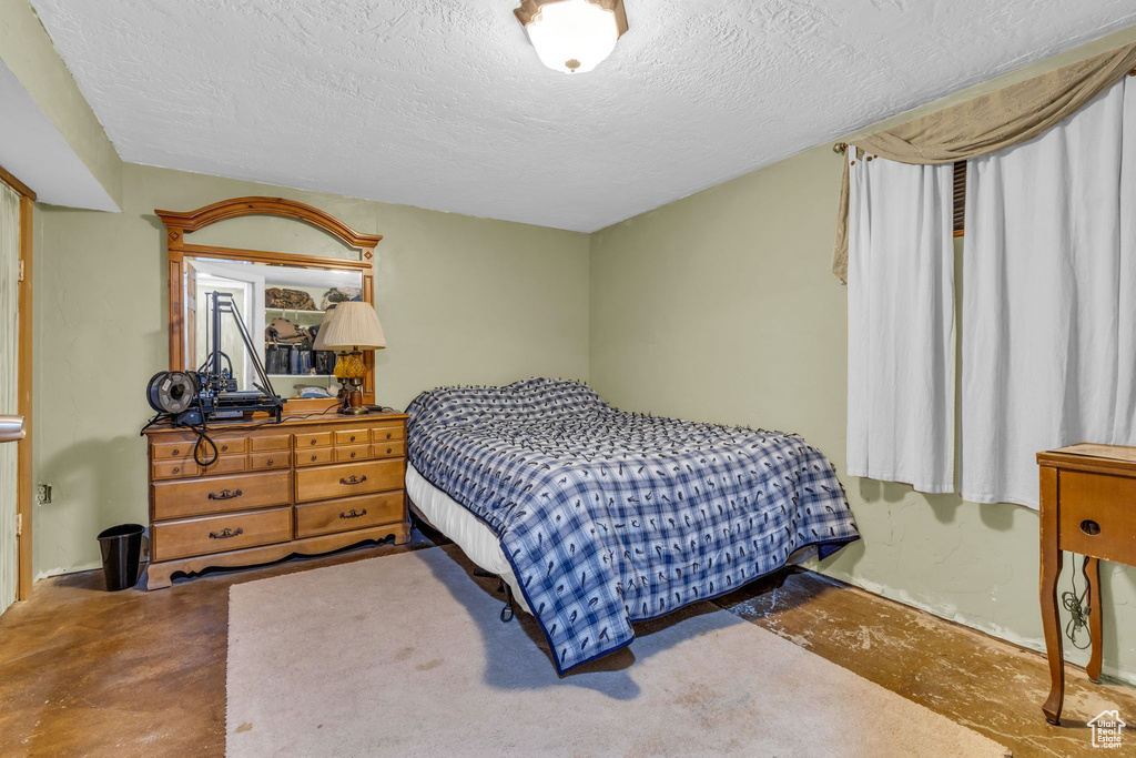 Bedroom with a textured ceiling and concrete flooring