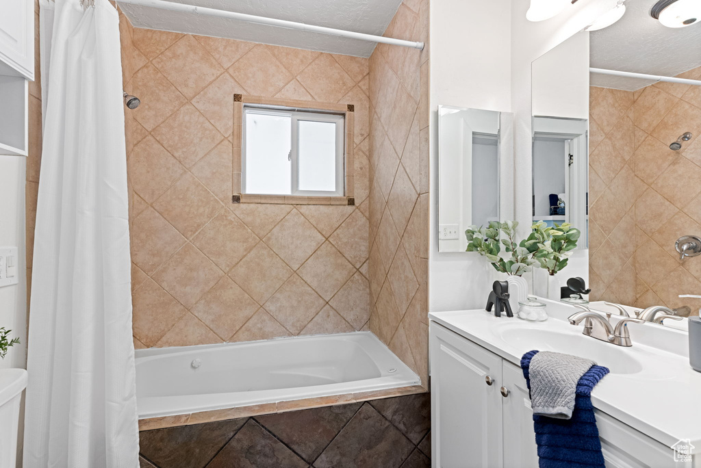 Full bathroom featuring a textured ceiling, toilet, vanity, and shower / tub combo with curtain