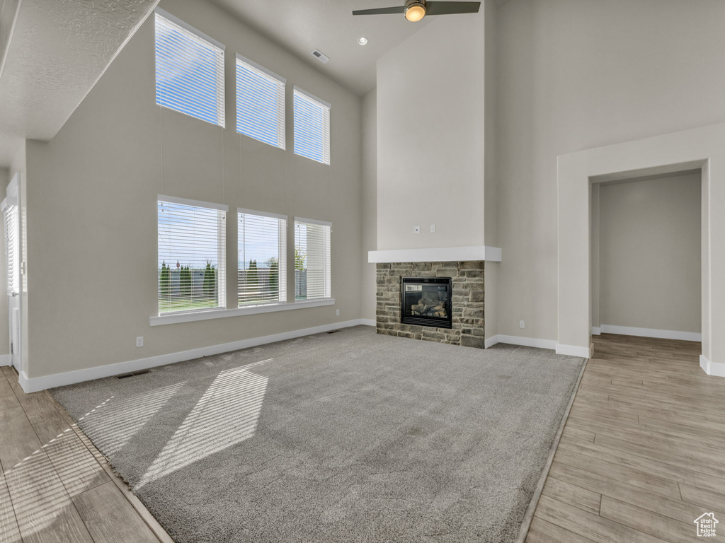 Unfurnished living room featuring a ceiling fan, baseboards, plenty of natural light, and a towering ceiling