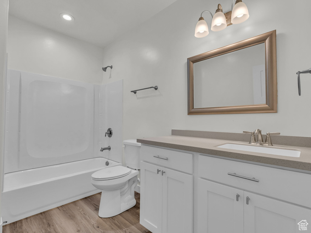Full bath featuring vanity, bathing tub / shower combination, toilet, and wood finished floors