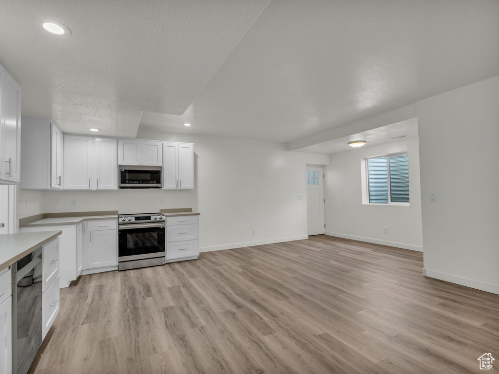 Kitchen with light countertops, light wood-style floors, stainless steel appliances, recessed lighting, and white cabinetry