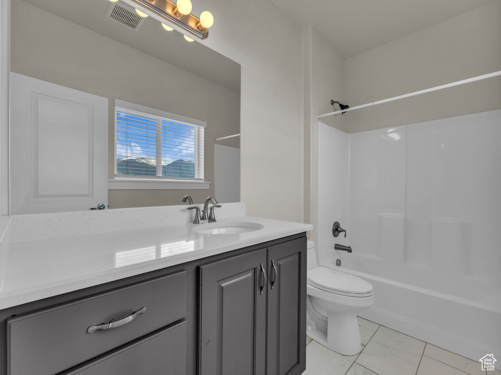 Bathroom featuring visible vents, vanity, marble finish floor, bathing tub / shower combination, and toilet