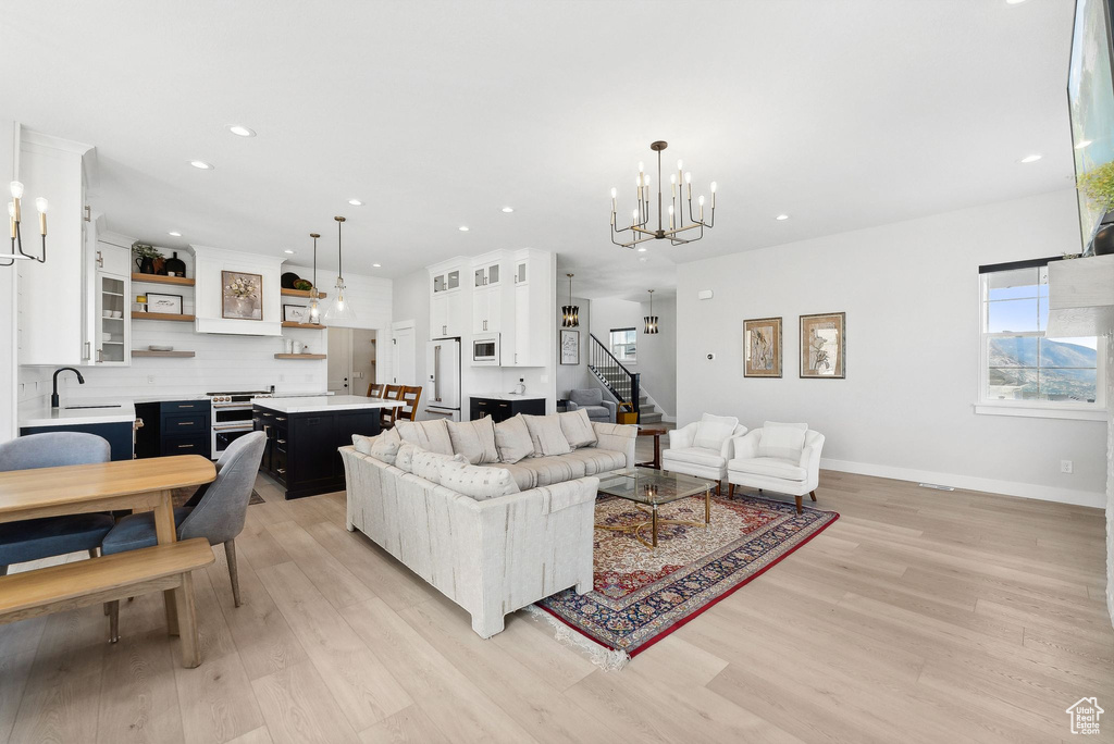 Living room featuring sink, light hardwood / wood-style floors, and an inviting chandelier