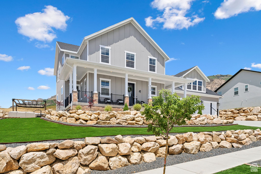 View of front of home with a garage, a front yard, and covered porch