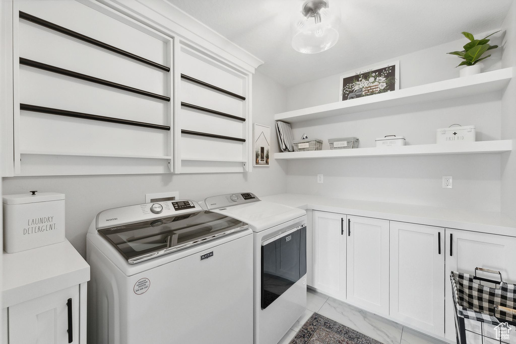 Laundry room featuring washer and clothes dryer, cabinets, and light tile flooring