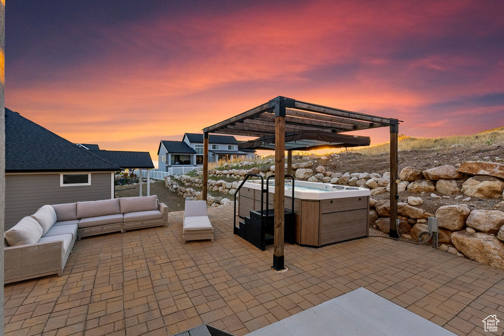 Patio terrace at dusk featuring a pergola, outdoor lounge area, and a hot tub