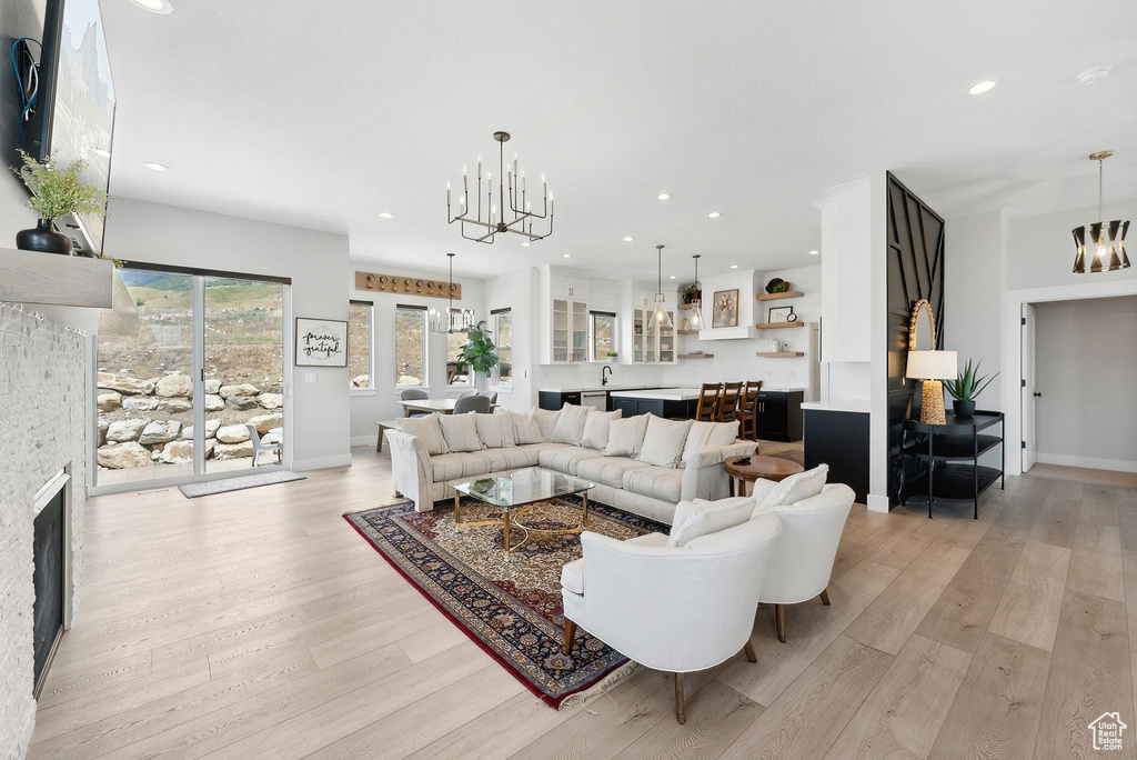 Living room with a notable chandelier, sink, light hardwood / wood-style floors, and a fireplace