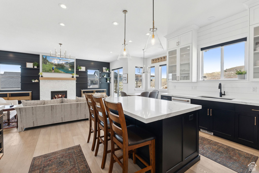 Kitchen featuring a center island, light hardwood / wood-style floors, white cabinets, and a breakfast bar area