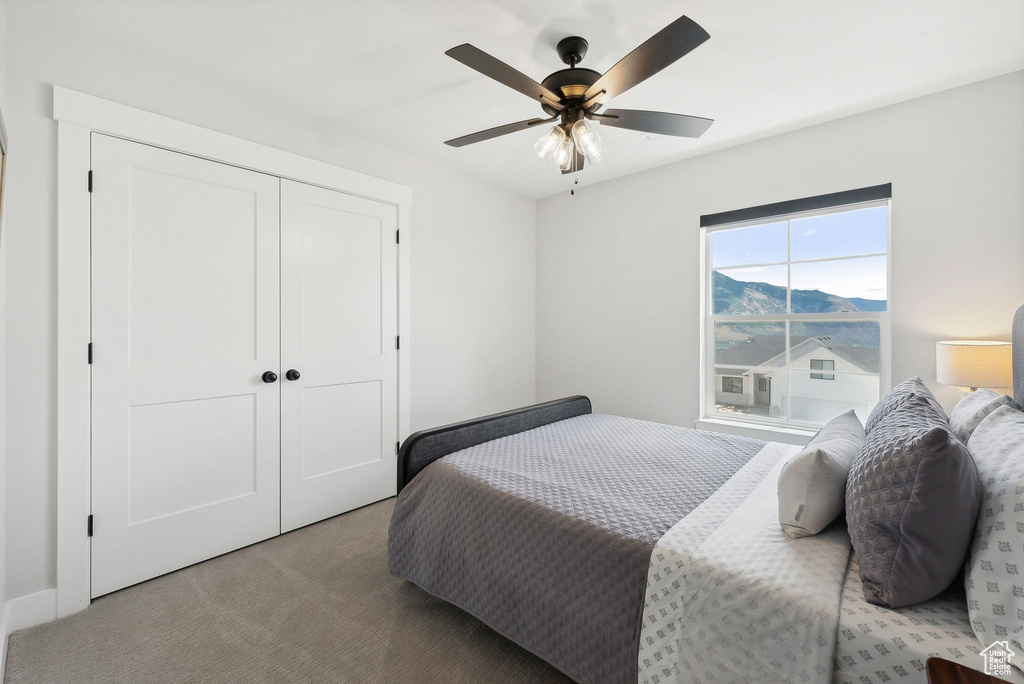 Carpeted bedroom with a closet and ceiling fan