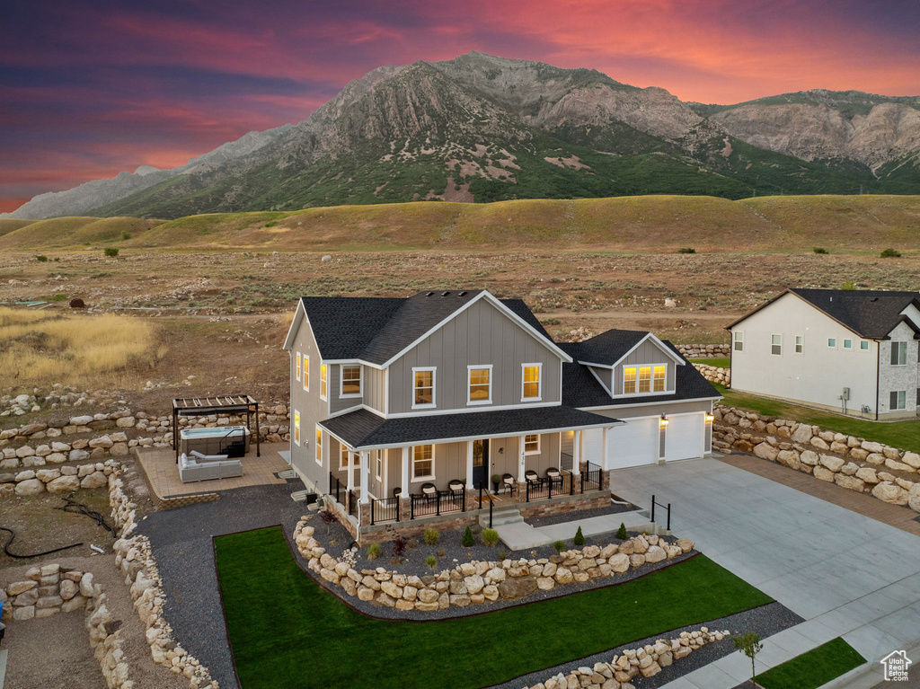 View of front facade with covered porch, a garage, and a mountain view