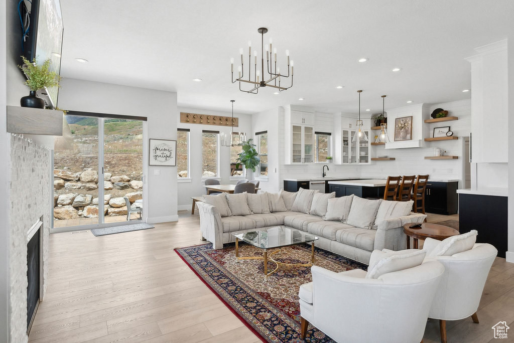 Living room with a fireplace, an inviting chandelier, and light hardwood / wood-style flooring