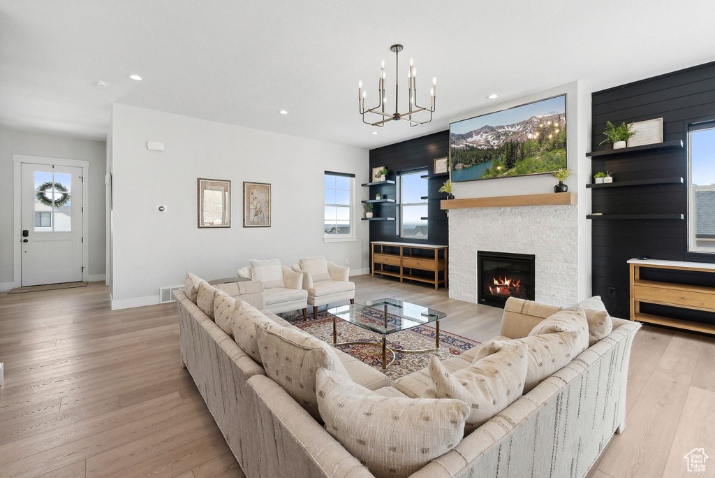 Living room featuring a chandelier, light wood-type flooring, and a fireplace