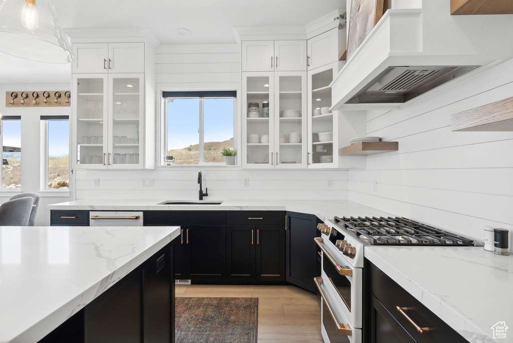 Kitchen with sink, custom range hood, white cabinetry, and high end stove