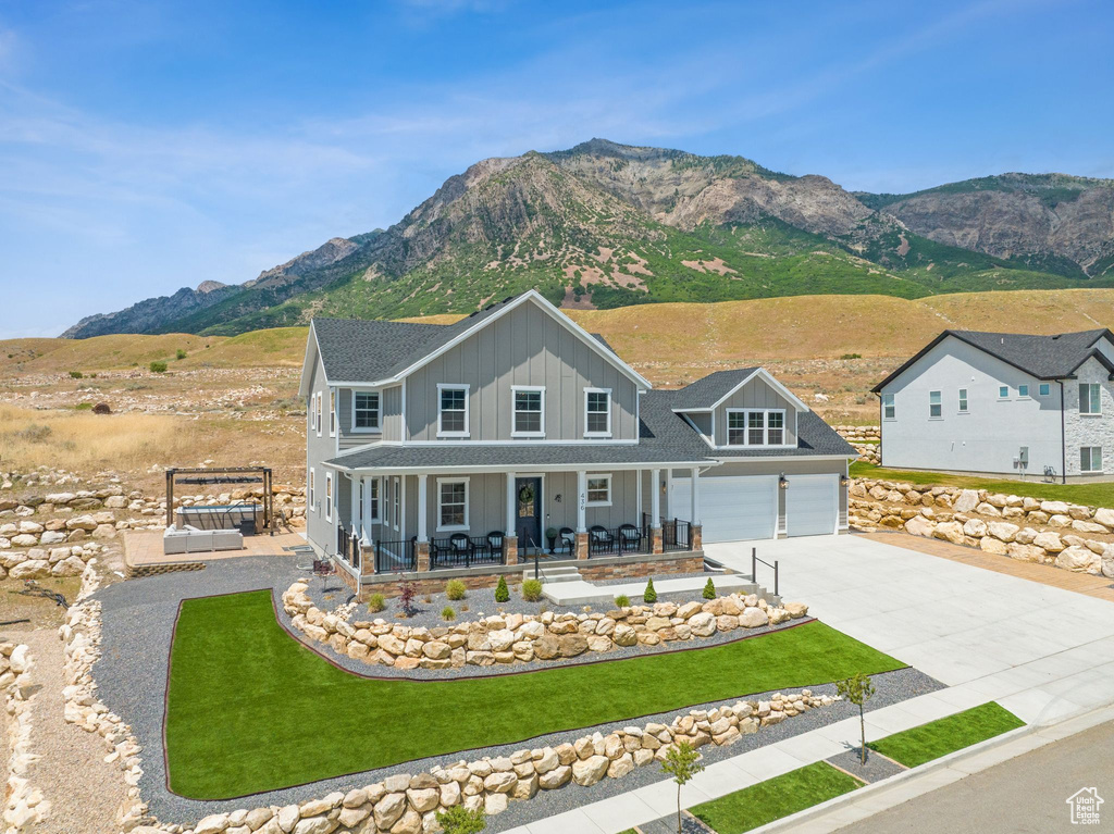 View of front of property featuring a front lawn, a garage, a mountain view, and covered porch