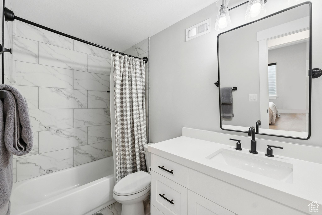 Full bathroom with vanity with extensive cabinet space, toilet, and shower / tub combo