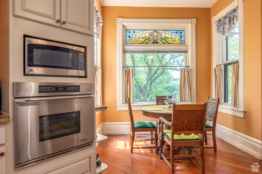 Kitchen with appliances with stainless steel finishes, white cabinetry, and hardwood / wood-style flooring