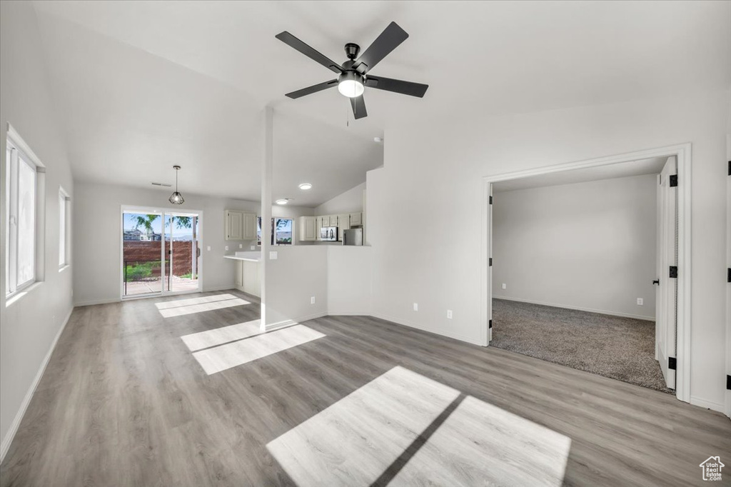 Unfurnished living room featuring lofted ceiling, light wood-type flooring, and ceiling fan