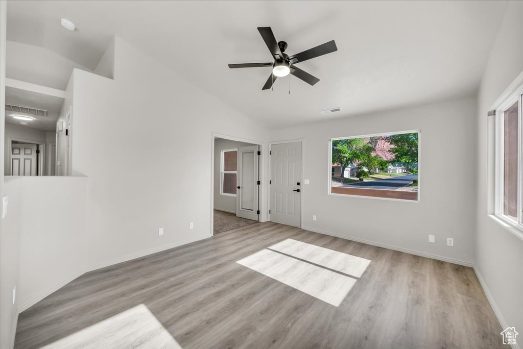 Empty room with lofted ceiling, ceiling fan, and light hardwood / wood-style flooring