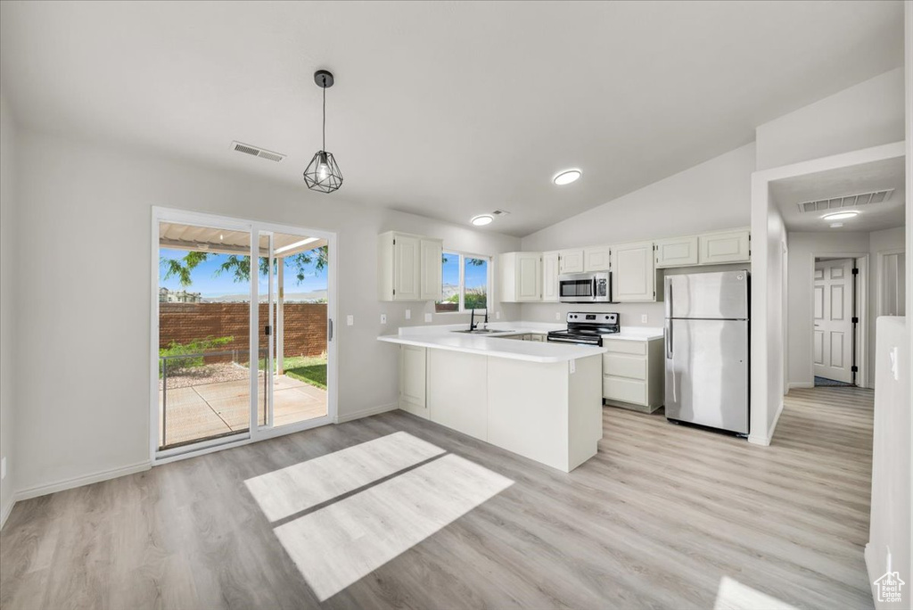 Kitchen featuring stainless steel appliances, vaulted ceiling, kitchen peninsula, and light wood-type flooring