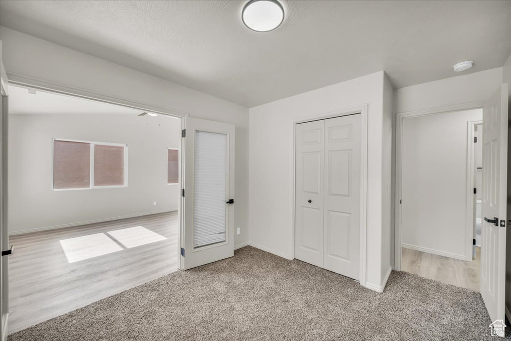 Unfurnished bedroom with light carpet and a closet