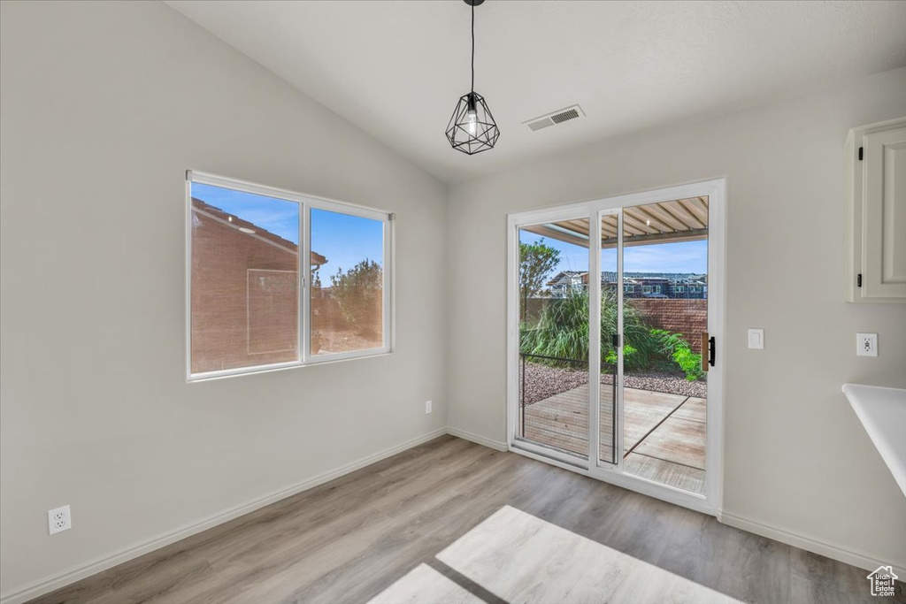 Unfurnished dining area featuring light hardwood / wood-style floors and vaulted ceiling