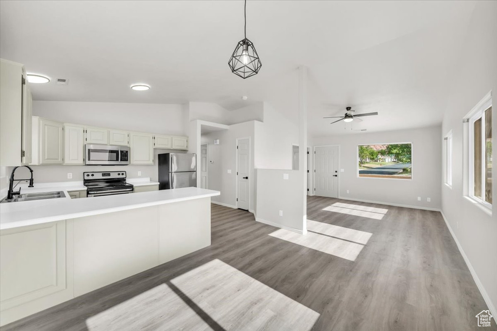 Kitchen with sink, vaulted ceiling, light wood-type flooring, and appliances with stainless steel finishes