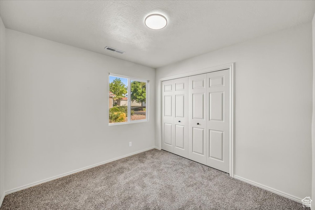 Unfurnished bedroom featuring carpet and a closet