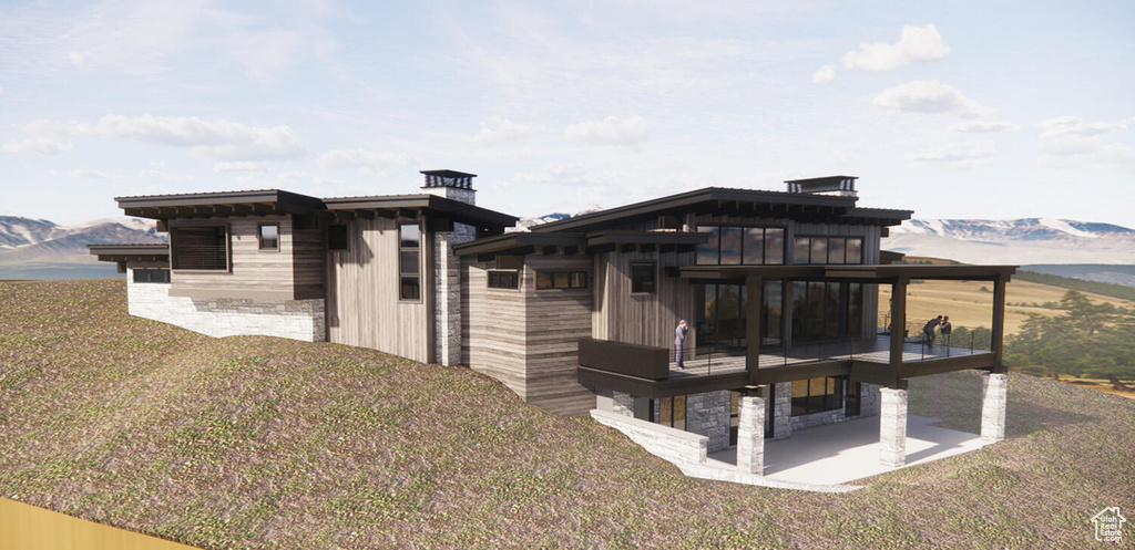 Rear view of property with a mountain view, a yard, and a patio