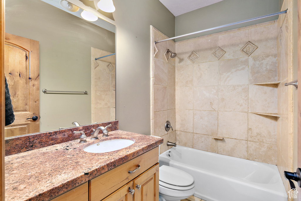 Full bathroom featuring large vanity, toilet, and tiled shower / bath combo