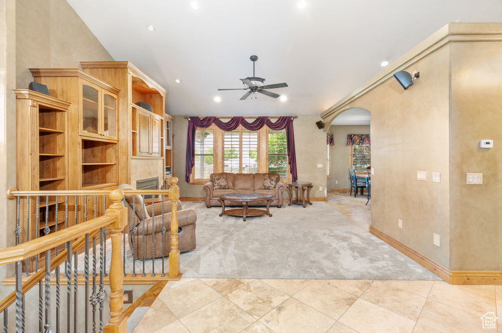 Living room featuring vaulted ceiling, ceiling fan, and light tile flooring