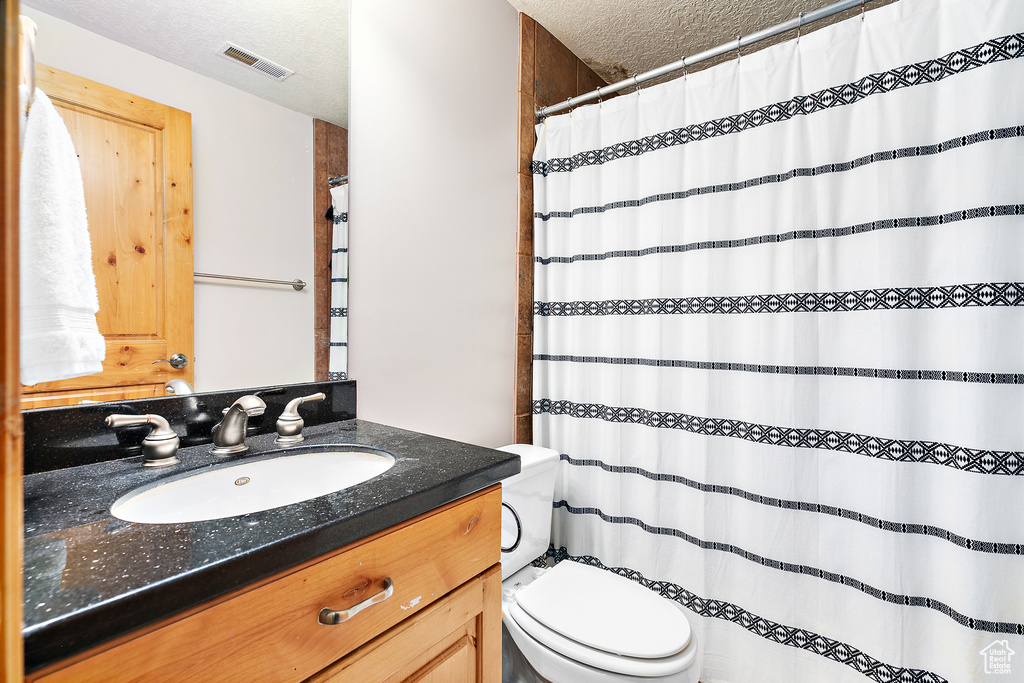 Bathroom featuring toilet, a textured ceiling, and large vanity