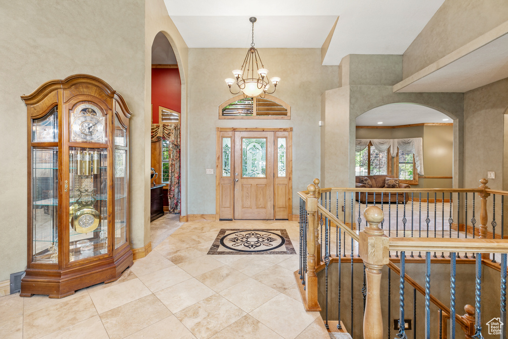 Tiled foyer with high vaulted ceiling and an inviting chandelier