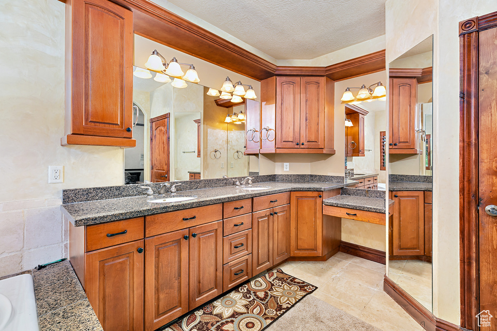 Interior space with light tile flooring, pendant lighting, dark stone countertops, a textured ceiling, and sink